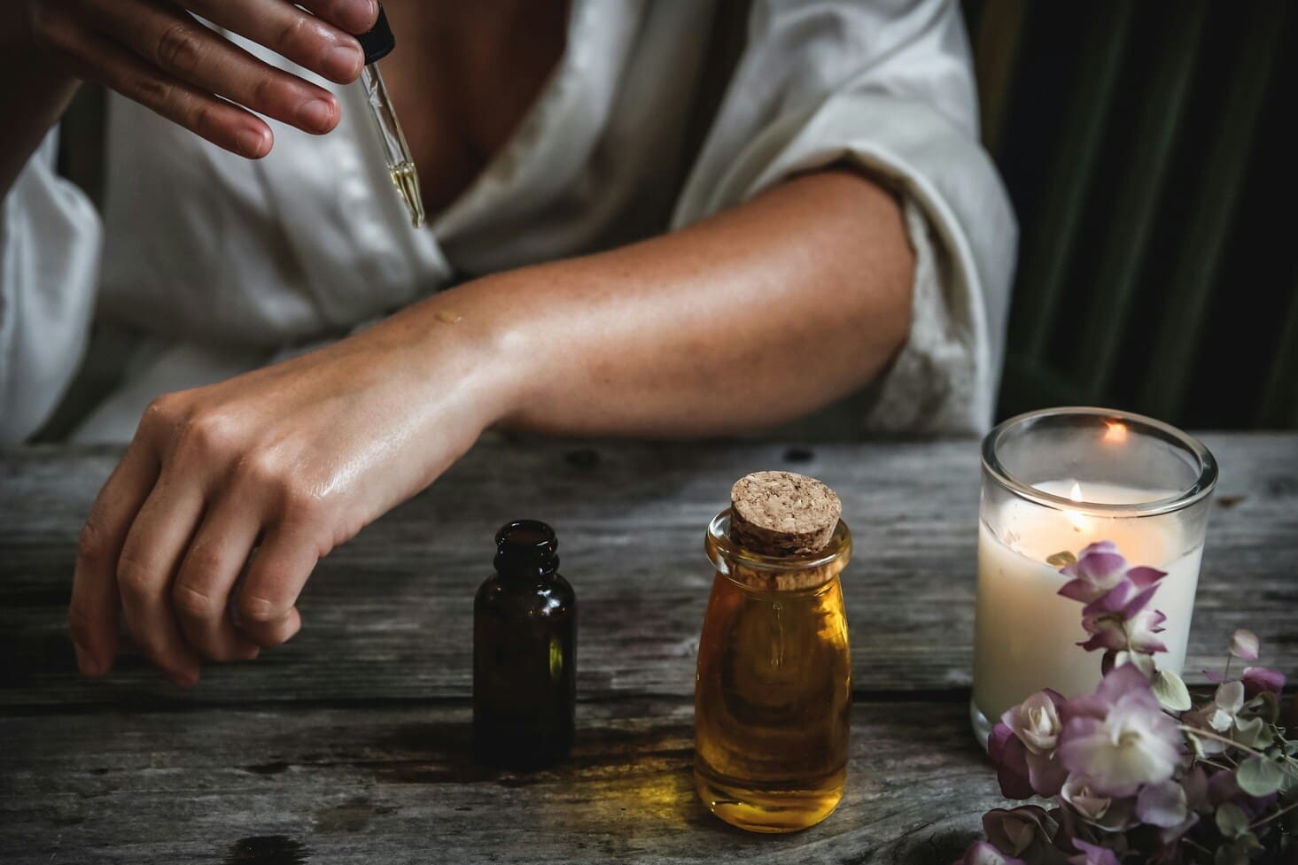 Flacons d'huiles essentielles, pipette et bougie pour un moment d'aromathérapie